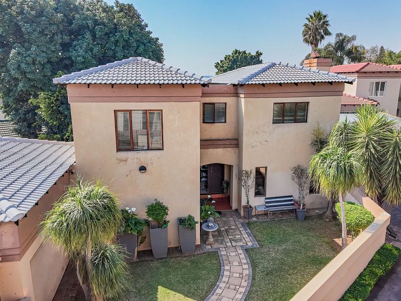 Elevated view of the townhouse front facade featuring a tiled roof, paved entrance walkway, and established garden area.