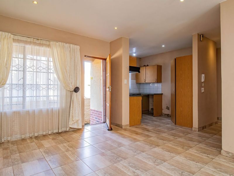 Open-plan living area featuring tiled flooring, recessed lighting, and an adjoining kitchen space with built-in cabinetry and an extractor fan.