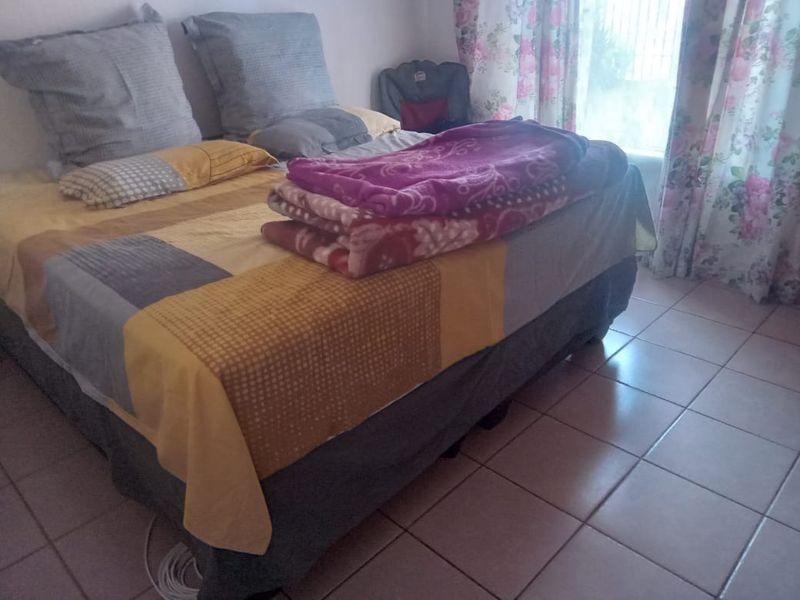 A bedroom featuring tiled flooring and natural light from the window.