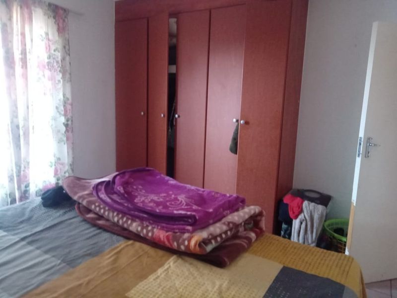 A bedroom featuring a large built-in wooden wardrobe and natural light from the window.