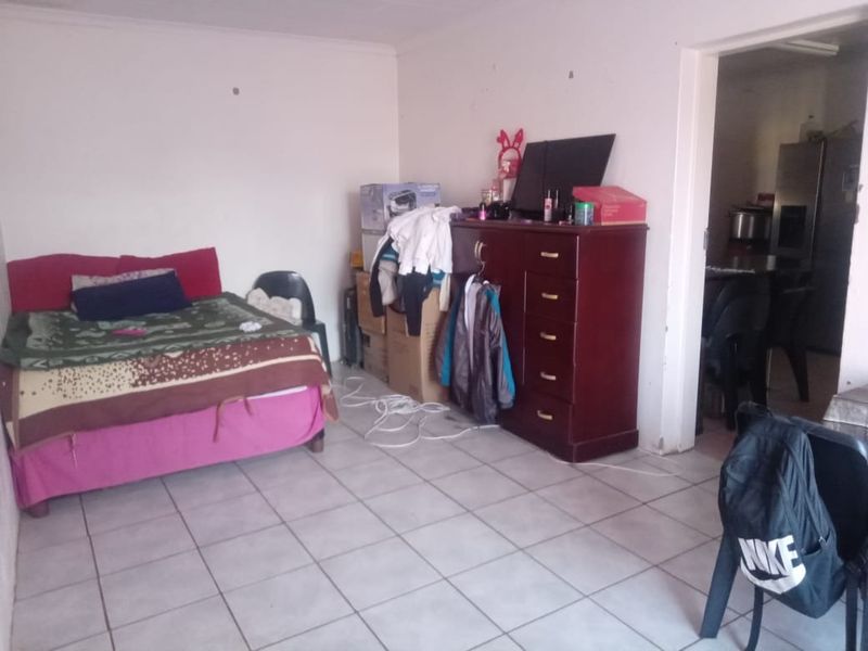 A living area featuring ceramic floor tiles, showing signs of wear on the walls and requiring cosmetic updates.