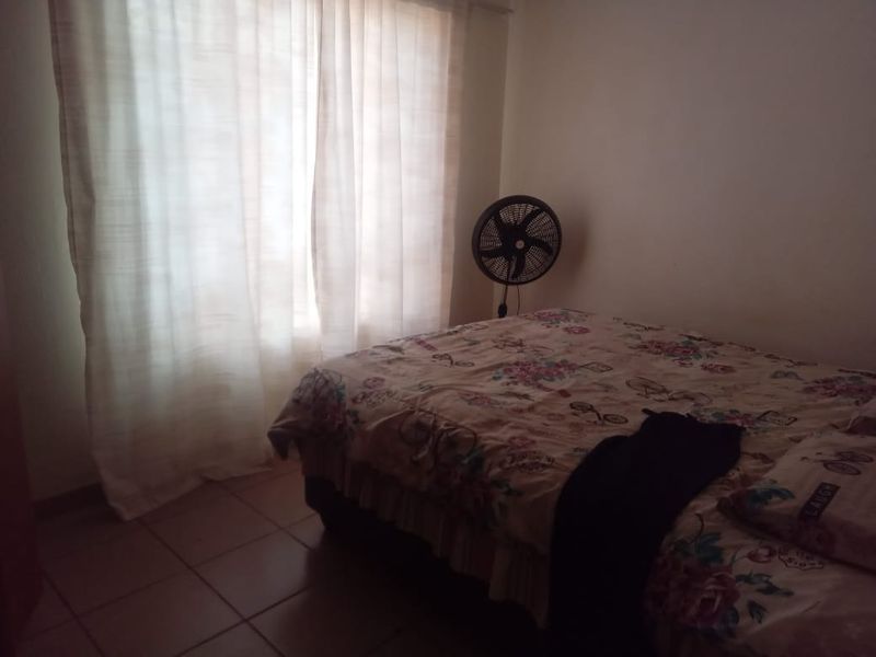 A standard bedroom featuring tiled flooring and window curtains, providing a functional living space.