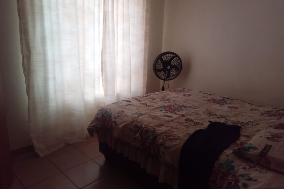 A standard bedroom featuring tiled flooring and window curtains, providing a functional living space.