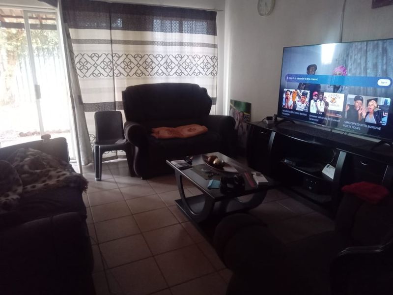 A living room featuring tiled flooring and a sliding glass door providing access to the exterior.