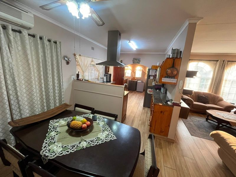 Open-plan living and kitchen area featuring tiled flooring, a central extractor fan, and a functional kitchen layout with granite countertops.