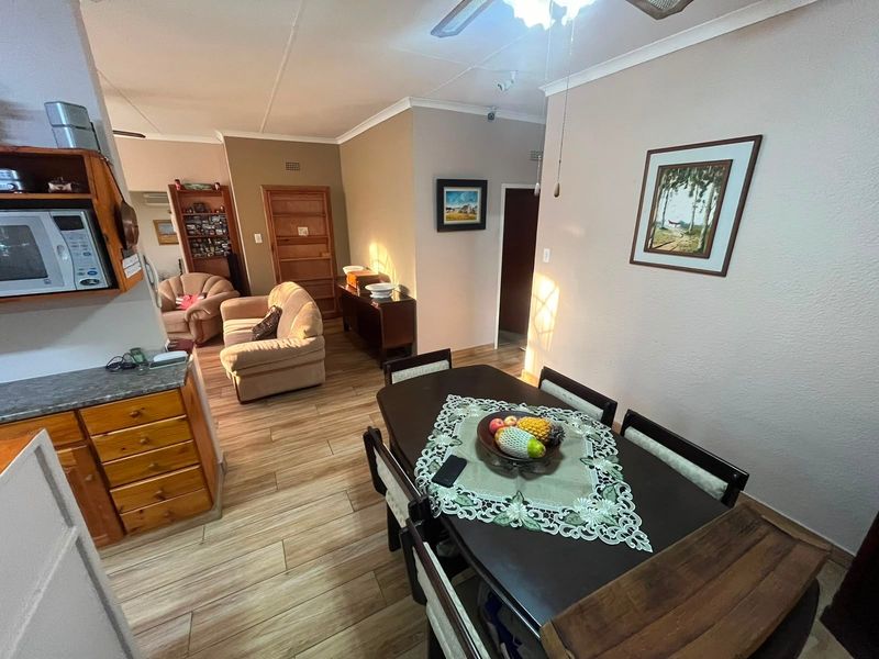Open-plan living and dining area featuring laminate flooring, built-in kitchen cabinetry, and a ceiling fan, creating a functional and connected living space.