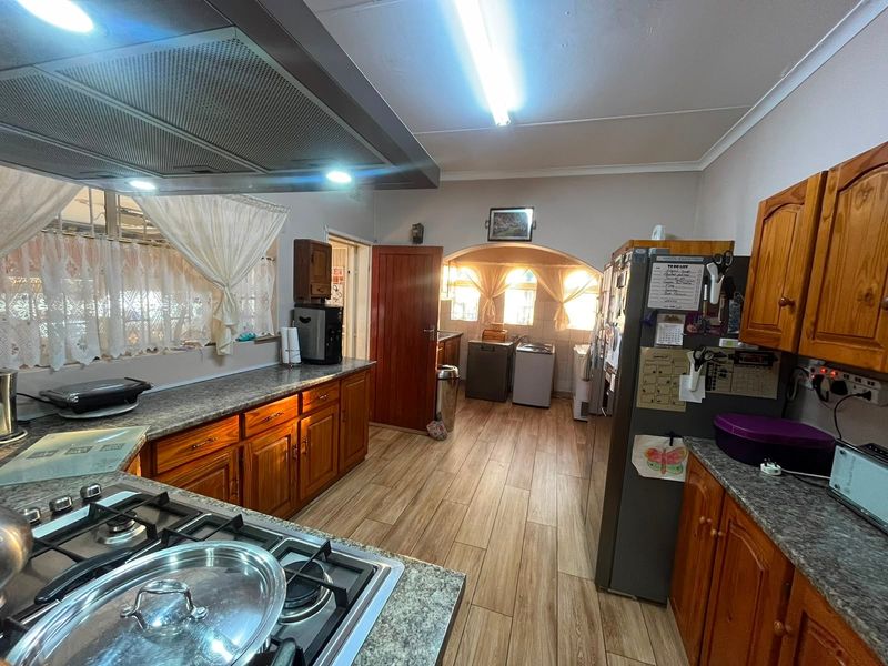 A functional kitchen featuring wooden cabinetry, laminate countertops, a gas hob with extractor fan, and wood-look laminate flooring.