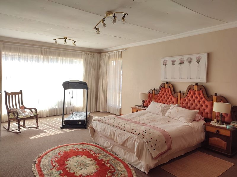 Spacious bedroom featuring large windows with natural light, carpeted flooring, and ceiling-mounted track lighting.