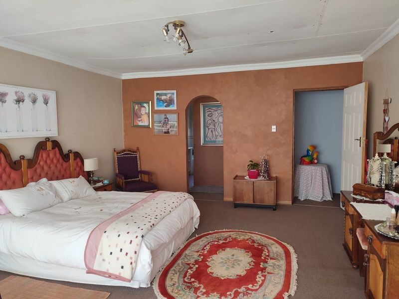 Spacious bedroom featuring an arched doorway, textured accent wall, and neutral carpeting, offering a functional layout with potential for cosmetic updates.