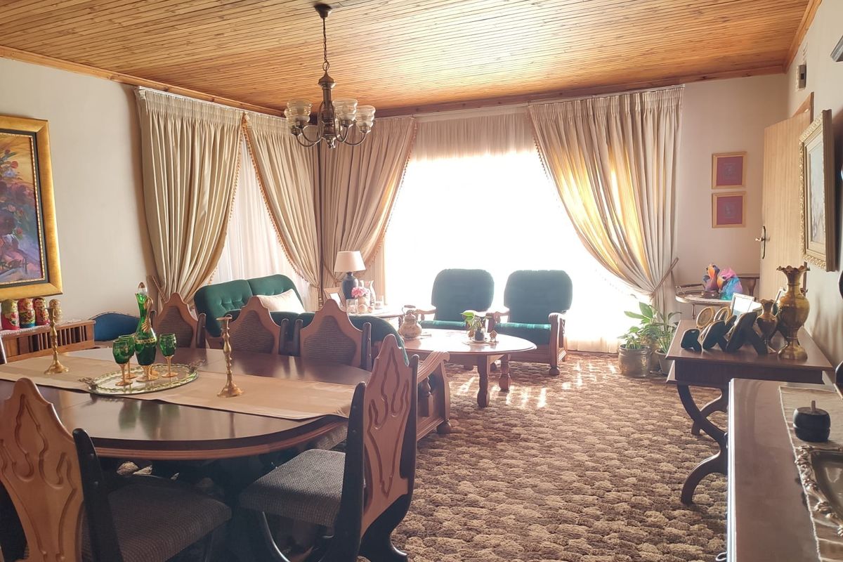 Spacious living and dining area featuring a distinctive timber-clad ceiling and large windows with floor-to-ceiling curtains.