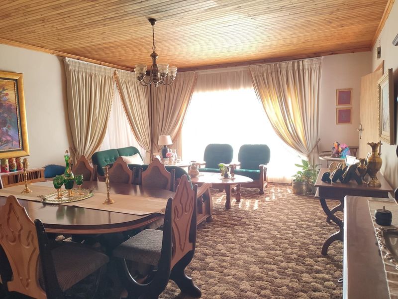 Spacious living and dining area featuring a distinctive timber-clad ceiling and large windows with floor-to-ceiling curtains.