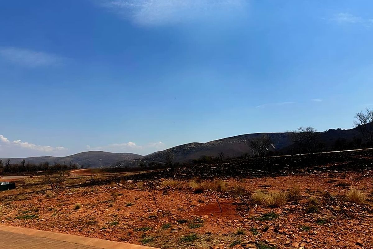 A wide-angle view of the vacant residential land featuring natural terrain and scenic mountain vistas in the background.