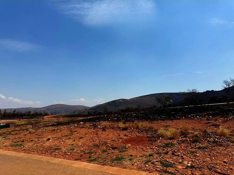 A wide-angle view of the vacant residential land featuring natural terrain and scenic mountain vistas in the background.