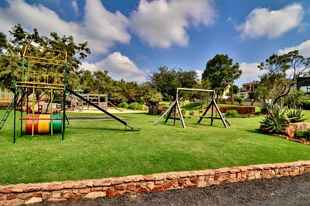 A well-maintained residential garden featuring a lawn, stone retaining wall, and integrated playground equipment.