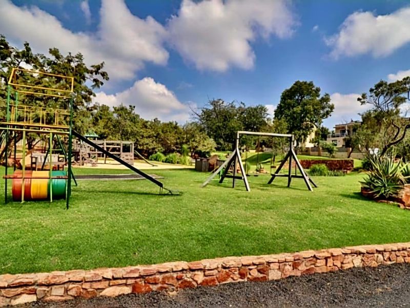 A well-maintained residential garden featuring a lawn, stone retaining wall, and integrated playground equipment.