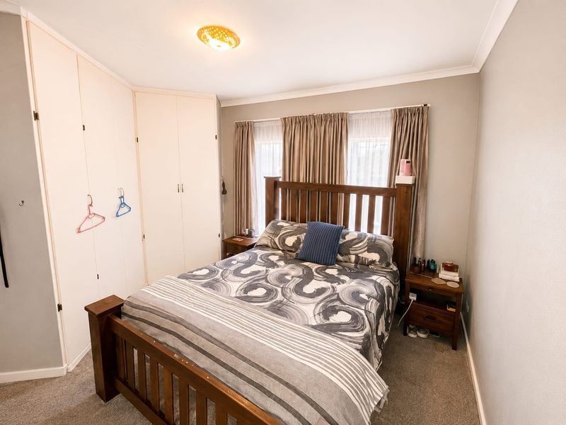 A functional bedroom featuring built-in cupboards, neutral wall finishes, and carpeted flooring, providing a comfortable and practical living space.