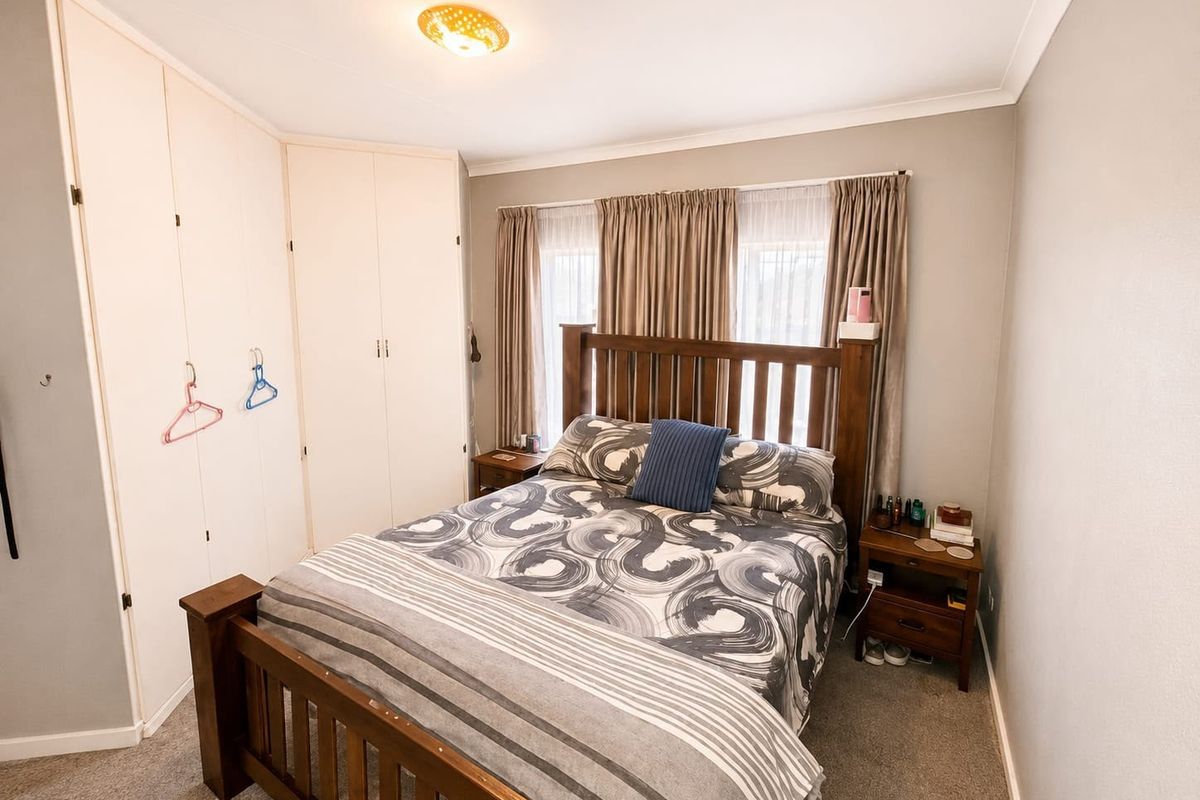 A functional bedroom featuring built-in cupboards, neutral wall finishes, and carpeted flooring, providing a comfortable and practical living space.