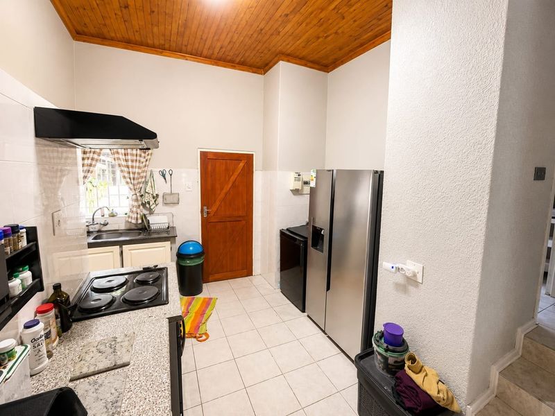 A functional kitchen featuring a built-in hob, extractor fan, tiled backsplash, and a distinctive wooden ceiling, providing a practical workspace.