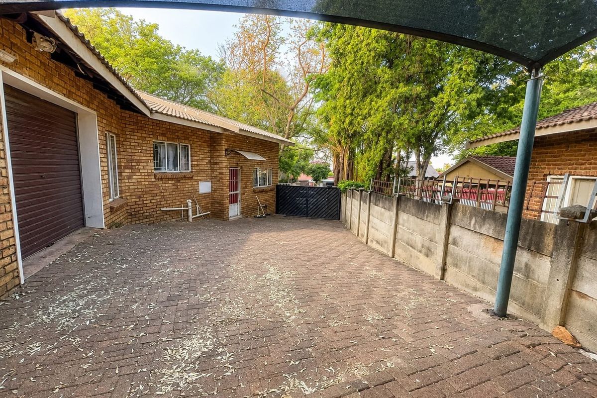 Rear exterior area featuring brick paving, a precast concrete boundary wall, and a shade sail structure providing cover for the outdoor space.