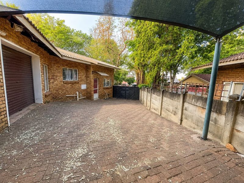 Rear exterior area featuring brick paving, a precast concrete boundary wall, and a shade sail structure providing cover for the outdoor space.