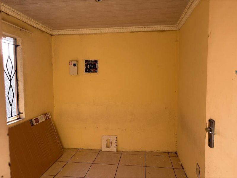 A small utility space featuring tiled flooring, timber ceiling, and exposed electrical infrastructure requiring maintenance and cosmetic updates.