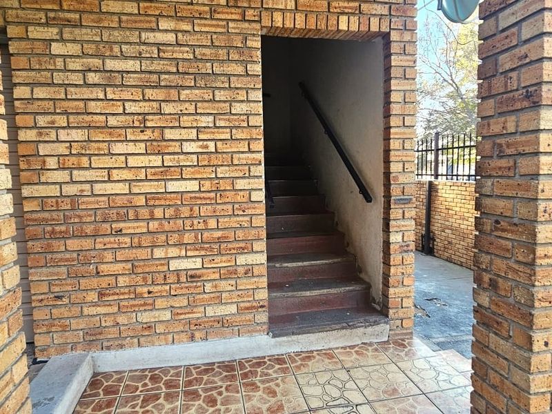 Exterior entrance area featuring face brick construction, a tiled porch, and a staircase leading to the upper level.