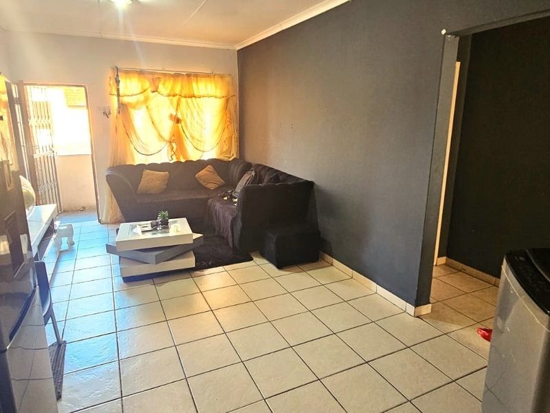 Open plan living area featuring ceramic floor tiles and dark accent walls, providing a functional space with direct access to an outdoor area.