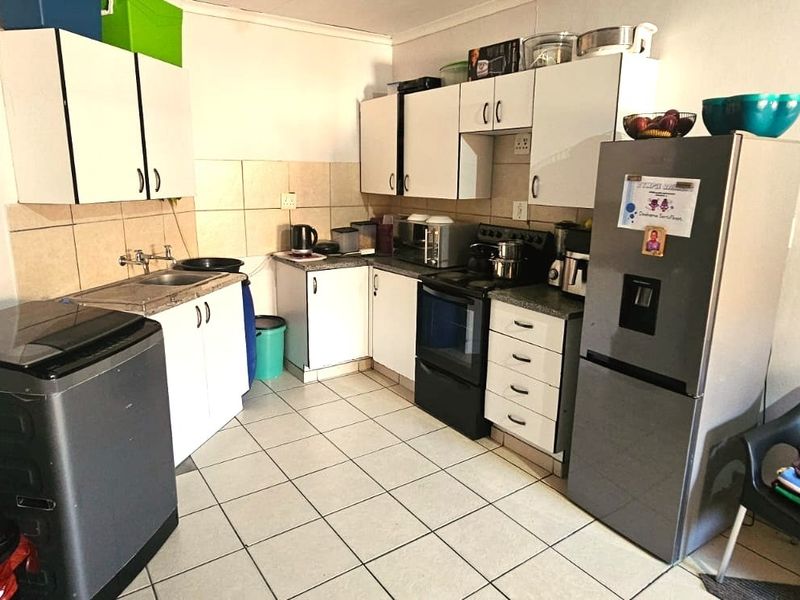 A functional kitchen featuring white cabinetry, tiled backsplash, tiled flooring, and a freestanding stove, offering a practical layout for daily meal preparation.