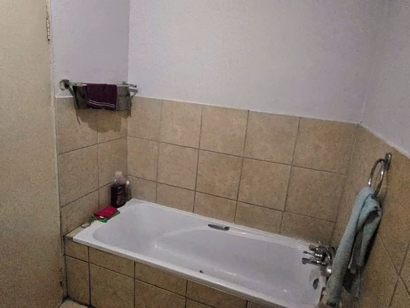 A functional bathroom featuring a built-in bathtub with tiled surround and wall-mounted towel rails.