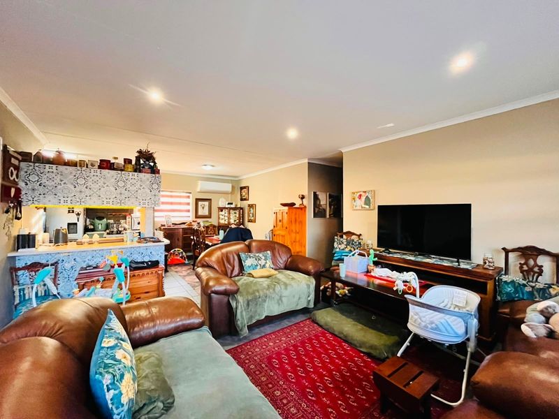 Open-plan living area featuring a kitchen with a decorative tiled breakfast bar, recessed lighting, and a wall-mounted split-system air conditioner.