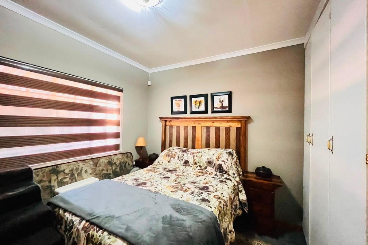 A functional bedroom featuring built-in cupboards, ceiling cornice detailing, and fitted roller blinds, providing a neutral base for personalization.