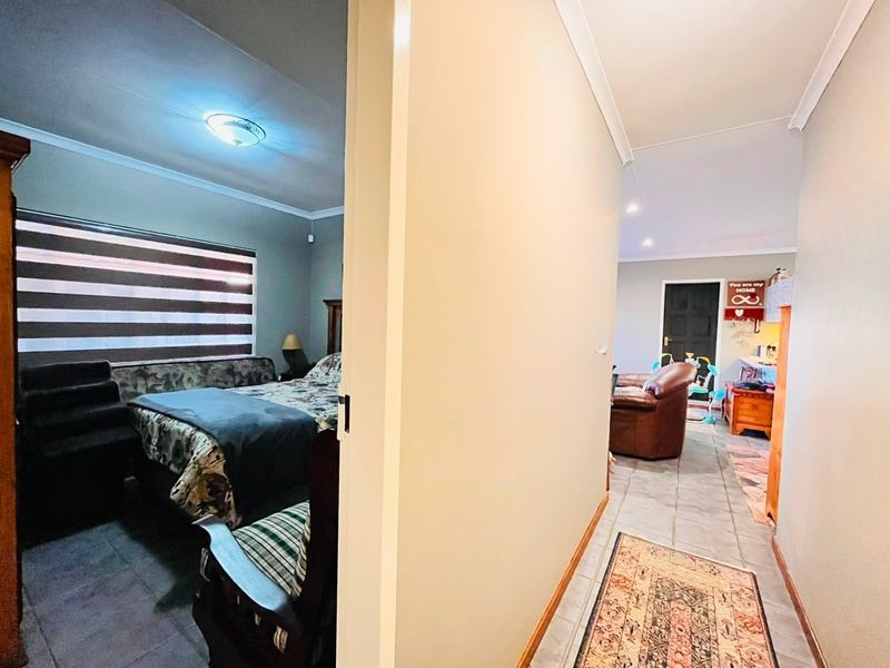 A view from a hallway looking into a bedroom and an adjacent living area, featuring tiled flooring and neutral wall finishes.
