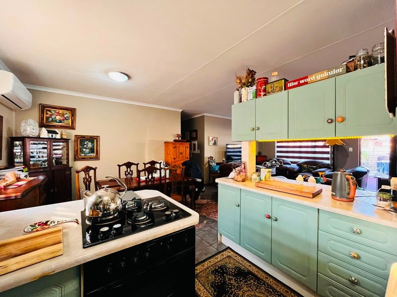 Open-plan kitchen and dining area featuring mint-green cabinetry, gas hob, built-in oven, and tiled flooring, creating a functional and connected living space.