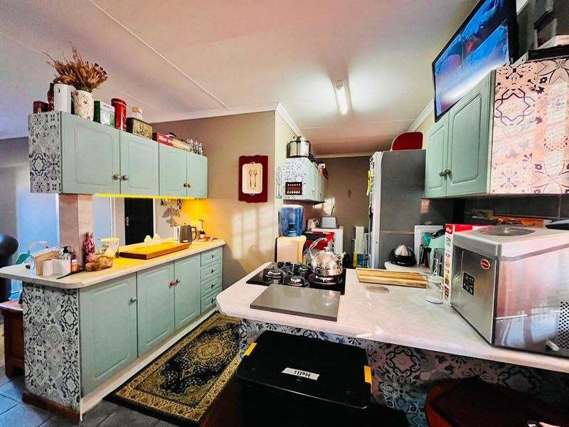 A functional kitchen featuring light green cabinetry, patterned tile accents, and a gas hob with ample counter space.