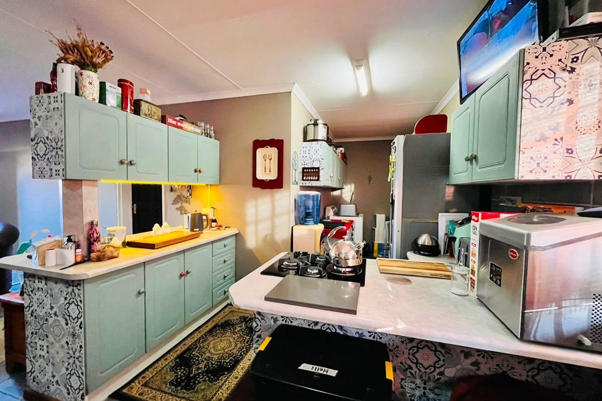 A functional kitchen featuring light green cabinetry, patterned tile accents, and a gas hob with ample counter space.