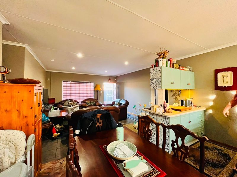Open-plan living and dining area featuring built-in kitchen cabinetry and tiled flooring, creating a functional and connected living space.