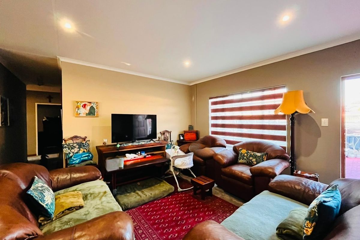 A comfortable living room featuring recessed downlights, zebra blinds, and a sliding door leading to the exterior.