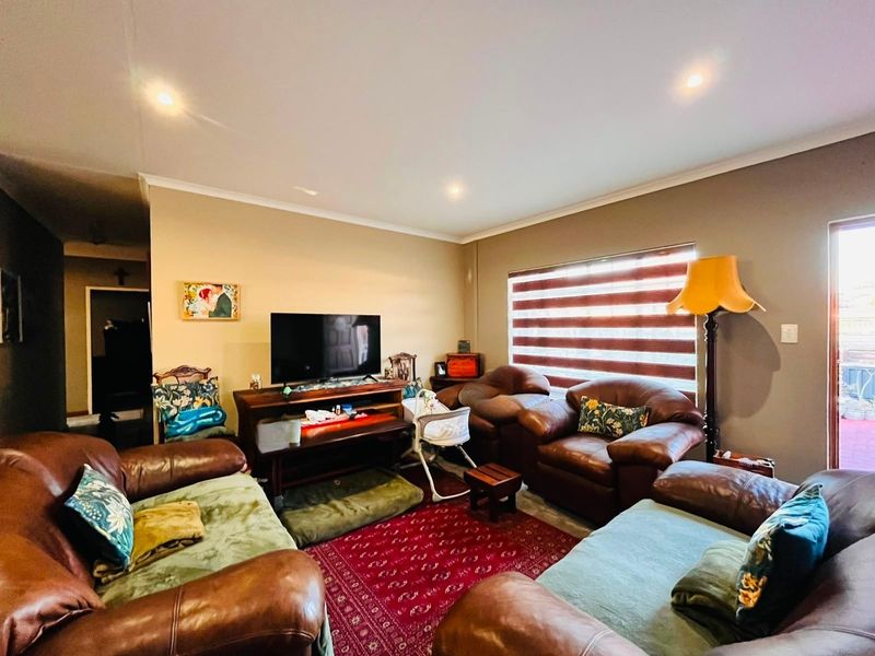 A comfortable living room featuring recessed downlights, zebra blinds, and a sliding door leading to the exterior.