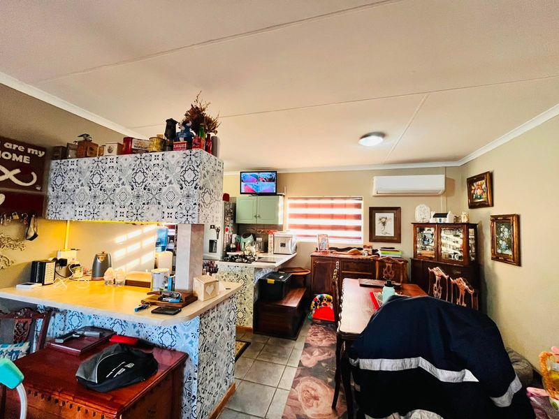 Open-plan living and kitchen area featuring tiled flooring, split-system air conditioning, and a central kitchen island with decorative tiling.