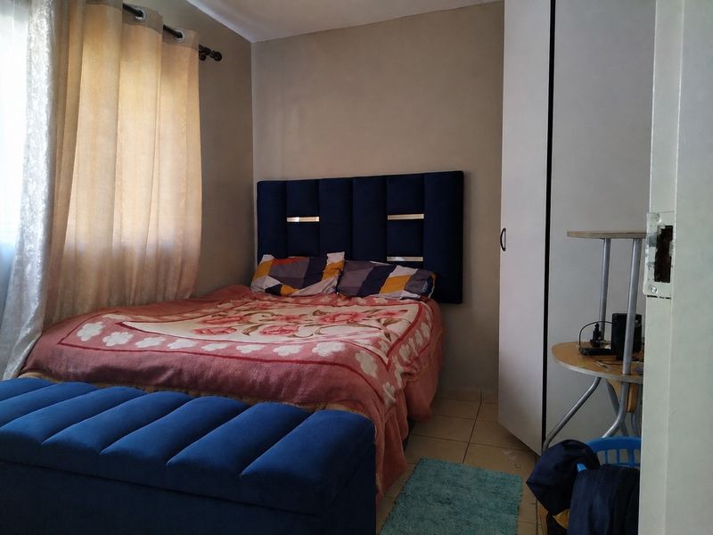 A functional bedroom featuring tiled flooring and a built-in wardrobe, providing essential storage space within the apartment.