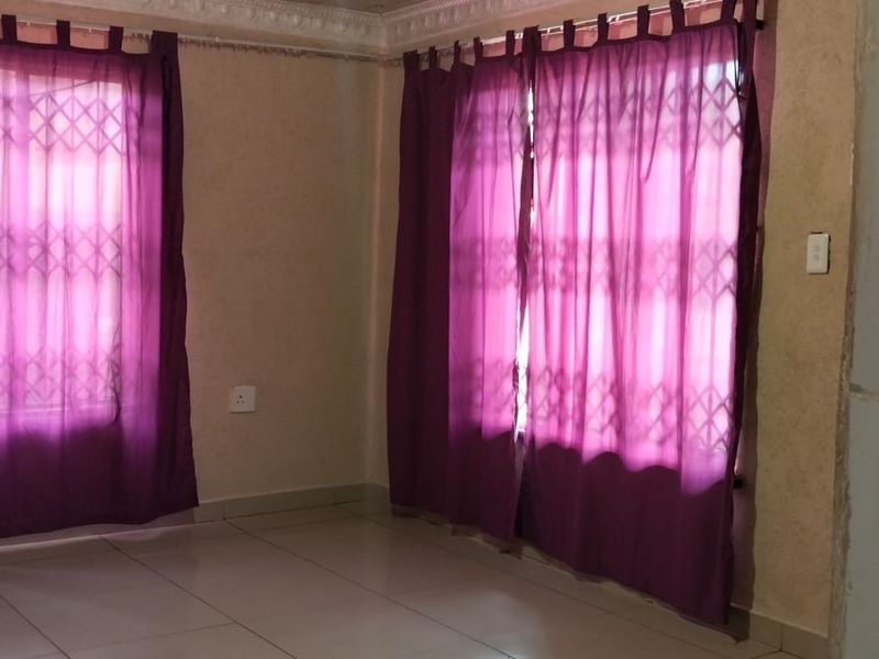 An empty living area featuring tiled flooring, decorative cornicing, and security gates on the windows.