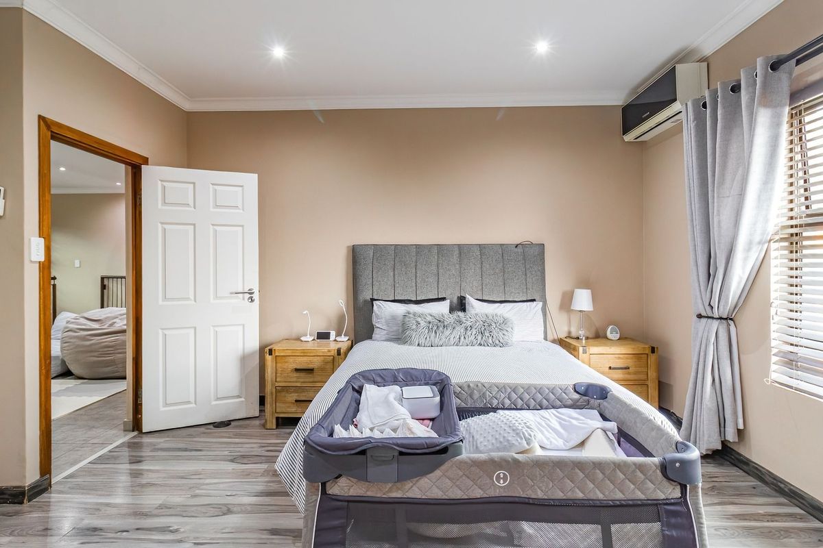 A well-maintained bedroom featuring laminate flooring, recessed downlighting, a split-system air conditioner, and built-in wardrobe storage.