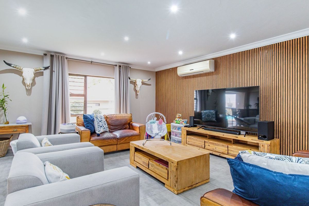 Spacious living room featuring a modern timber slat feature wall, recessed downlighting, tiled flooring, and a wall-mounted split-system air conditioner.