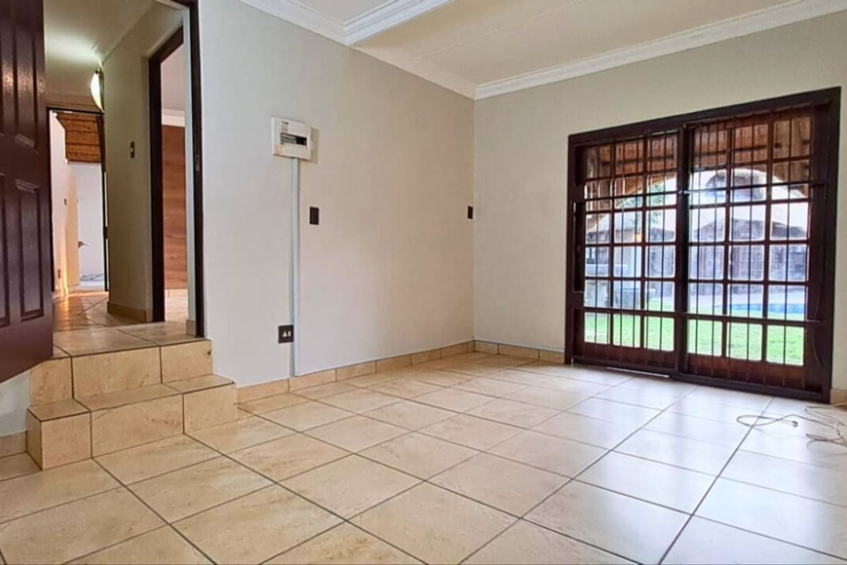 An empty living room featuring tiled flooring, coved ceilings, and a sliding glass door providing access to the outdoor area.