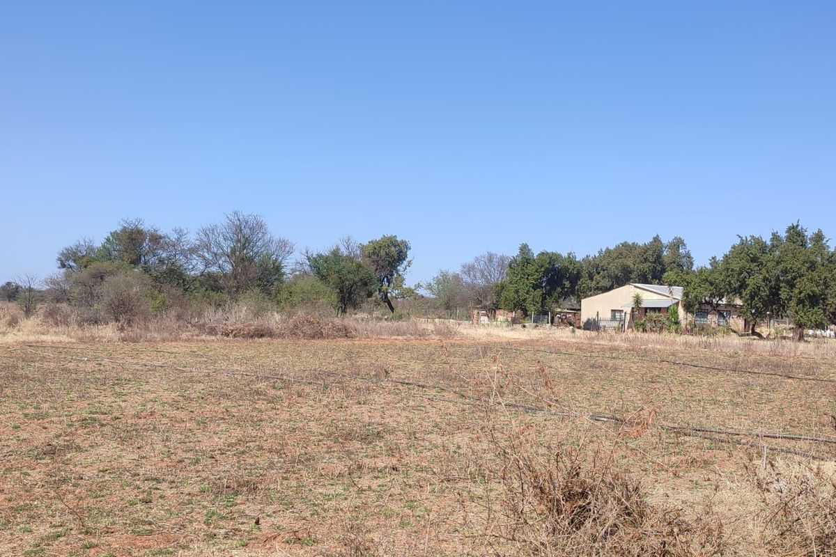 A wide view of the farm property featuring open land, irrigation infrastructure, and the main dwelling visible in the background.
