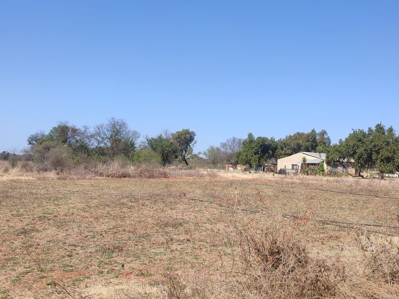 A wide view of the farm property featuring open land, irrigation infrastructure, and the main dwelling visible in the background.