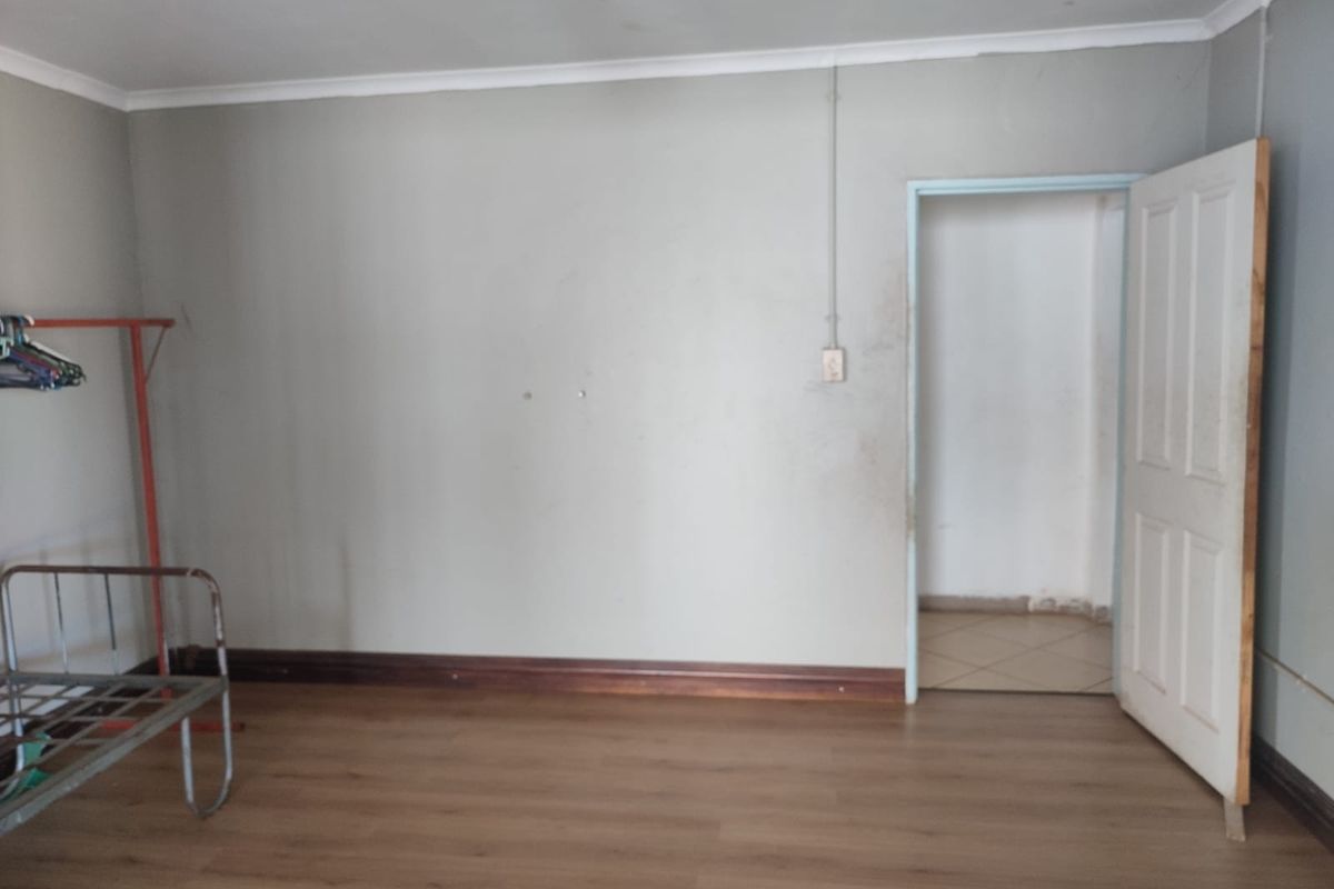 A vacant bedroom featuring laminate flooring, neutral walls, and a standard internal door, offering a blank canvas for potential renovation or styling.