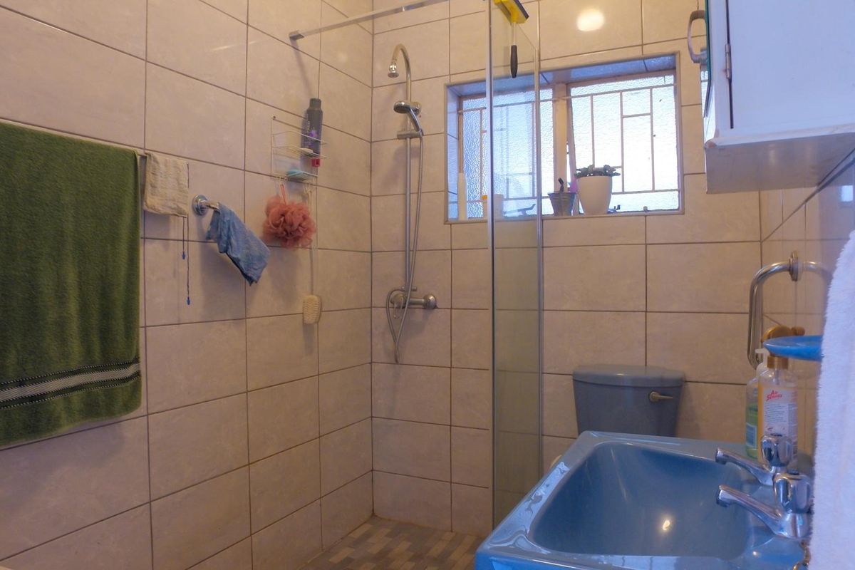 A functional bathroom featuring tiled walls, a glass-enclosed shower, a toilet, and a blue basin with chrome fixtures.