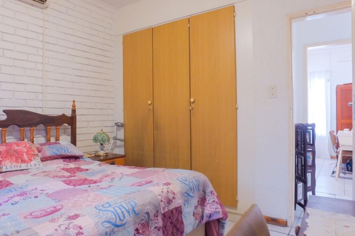 A bedroom featuring built-in wooden cupboards, an exposed brick feature wall, and an integrated air conditioning unit.