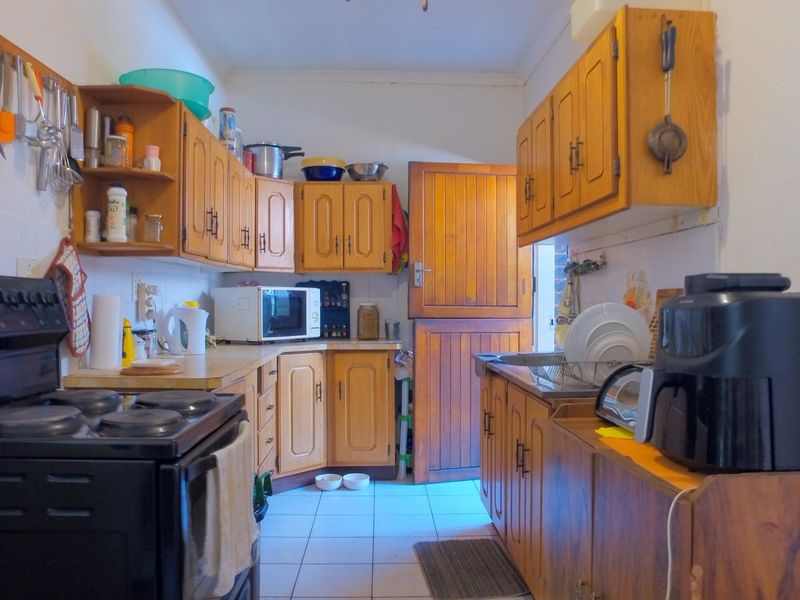 A functional kitchen featuring traditional wooden cabinetry, tiled flooring, a built-in stove, and a classic dutch door leading to the exterior.